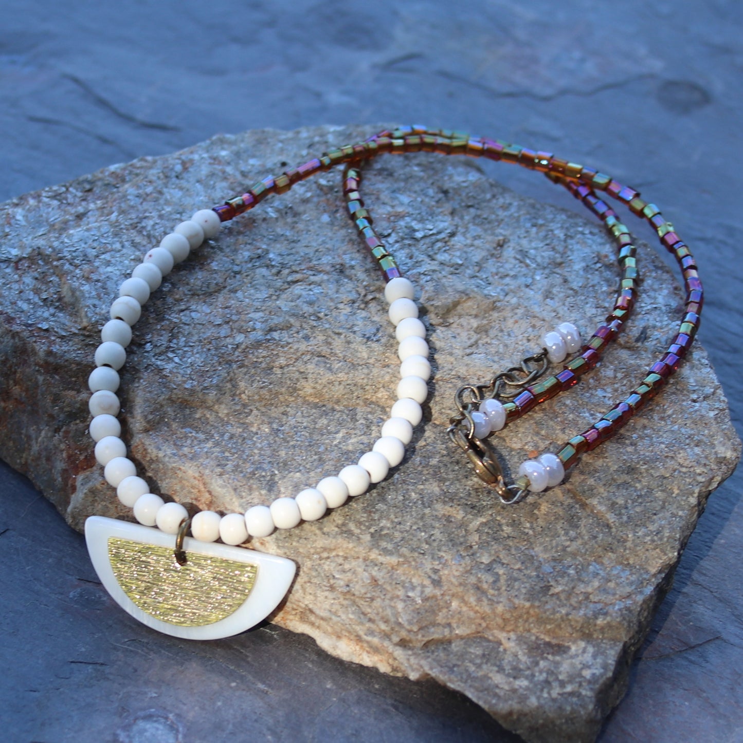 Half circle shell and brass pendant on white and topaz beaded necklace. 18" adjustable necklace