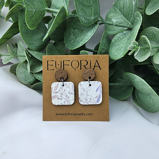 Cork over leather square earrings with round wood post. .75" squares with a delicate, barely there leaves and floral pattern in pale greys and purples over a white field.