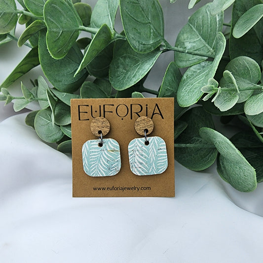 Cork over leather square earrings with round wood post. .75" squares with white tropical leaves over a seafoam field.