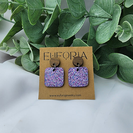 leather square earrings with round wood post. .75" squares in blue, silver and magenta micro glitter.