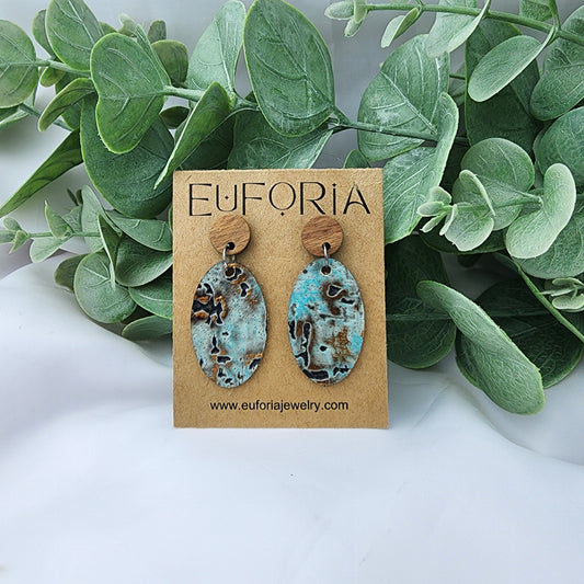 leather oval earrings with round wood post. 1.25" ovals with rustic looking driftwood print in aqua, bronze and charcoal.